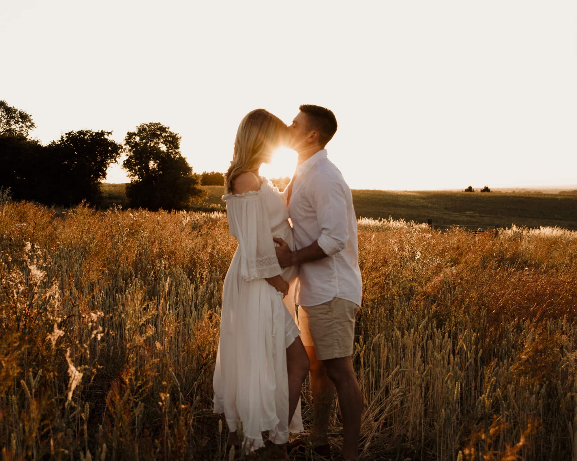 couple kissing in the sunset during a cleckheaton maternity photography photoshoot in a corn field