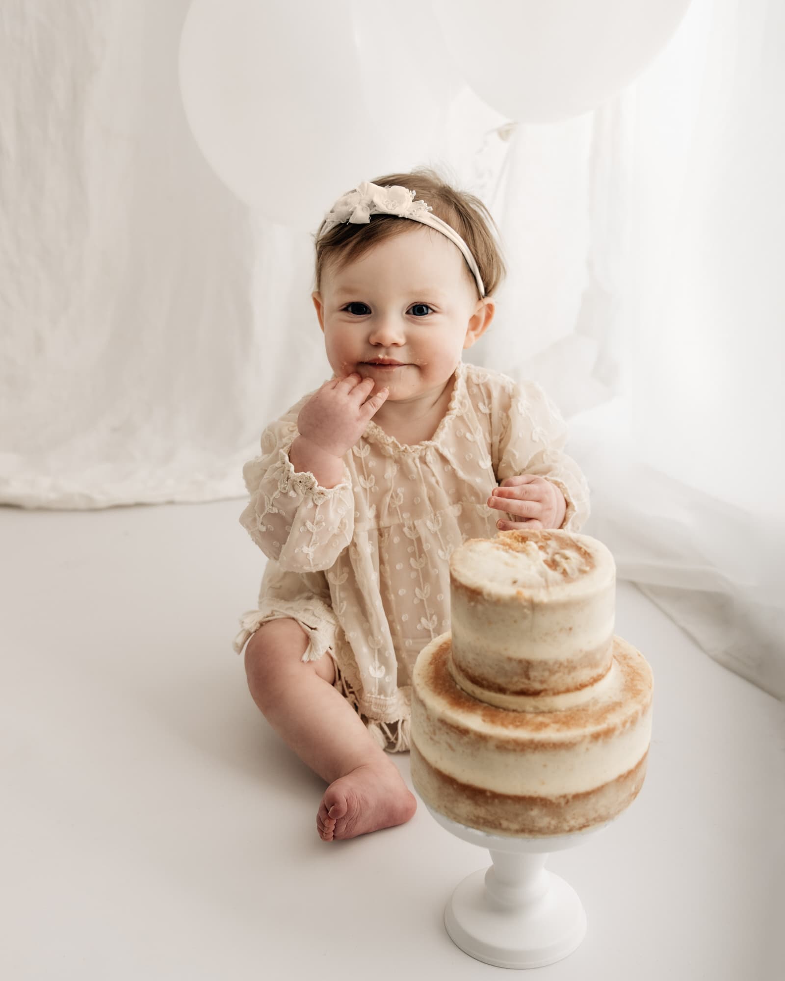 baby smiling behind a 2 tier cake during a bradford cake smash photographer photoshoot