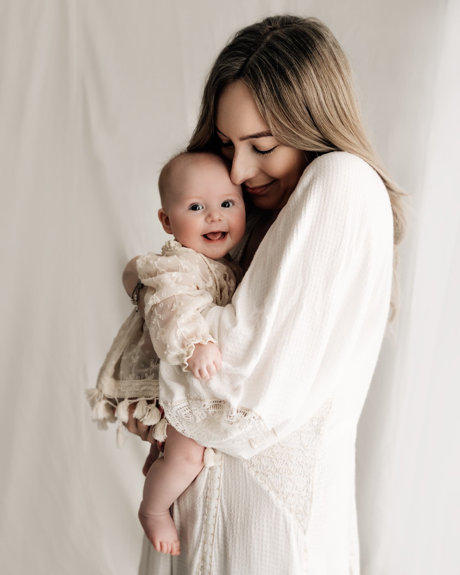 mother holding her baby and baby smiling during a photoshoot in a leeds photography studio