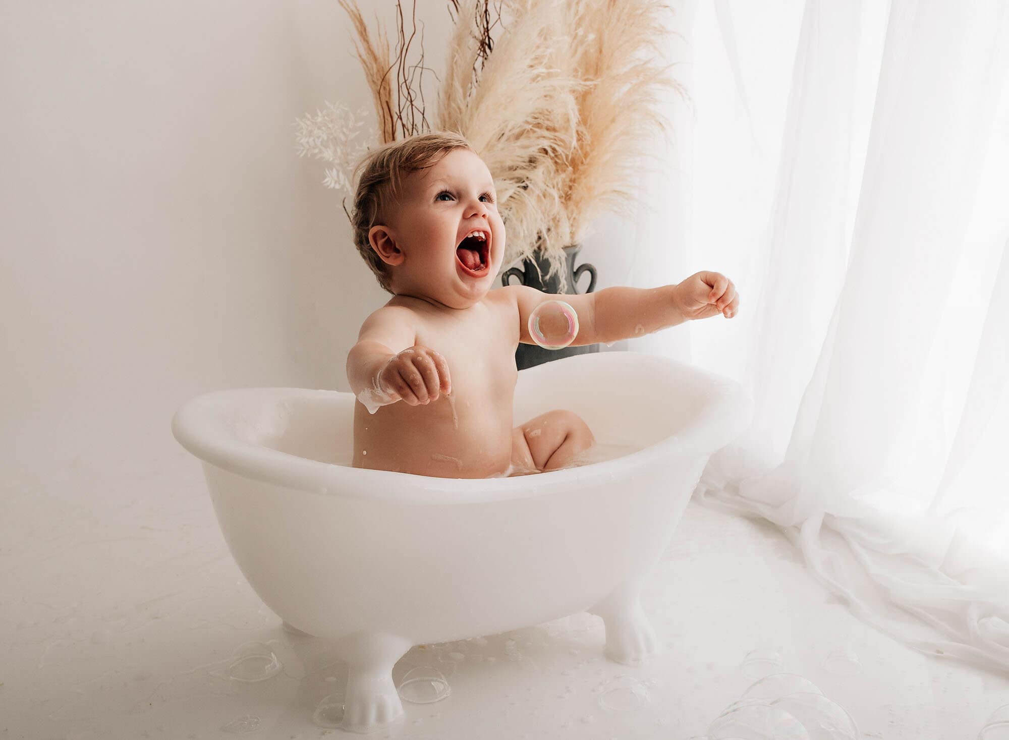 happy baby in a bath at a bradford cake smash potographer shoot
