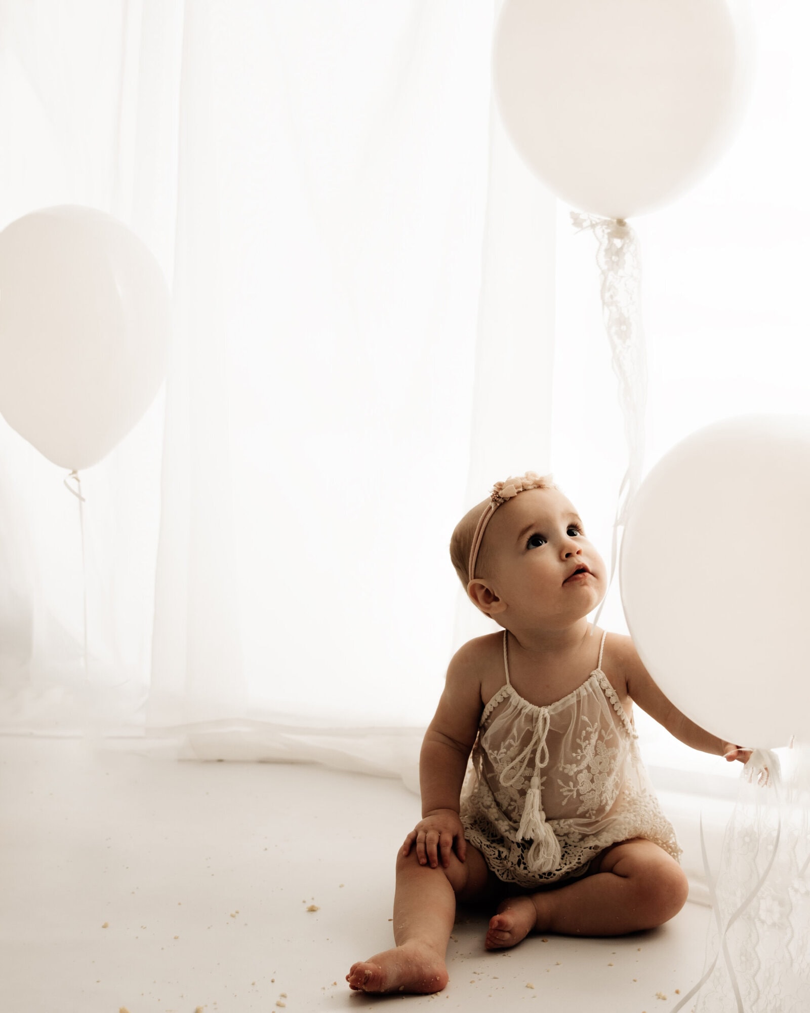 baby girl holding balloons during a bradford cake smash photoshoot